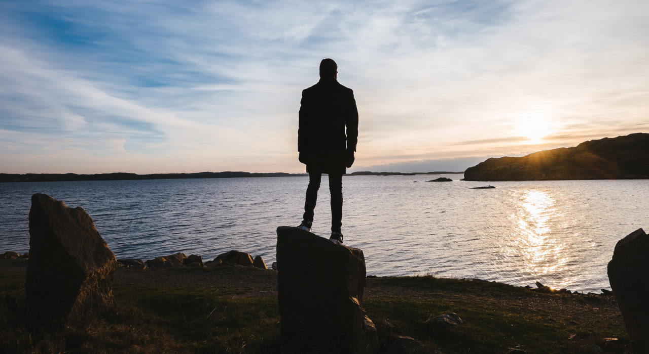 A man standing on a rock and watching sunset