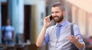 Handsome hipster with beard walking in town and calling on mobile phone