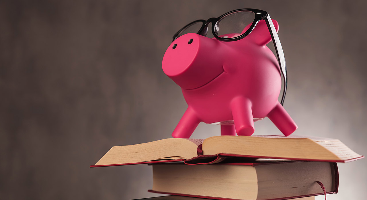 side of a piggy bank wearing glasses standing on books