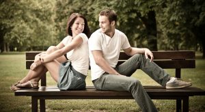 Young smiling couple looking on each other - sitting on bench