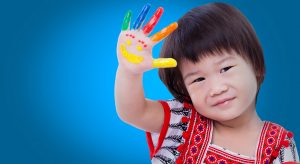 Adorable little thai girl painting her palm, colorful right hand raised up and painted with smiling face