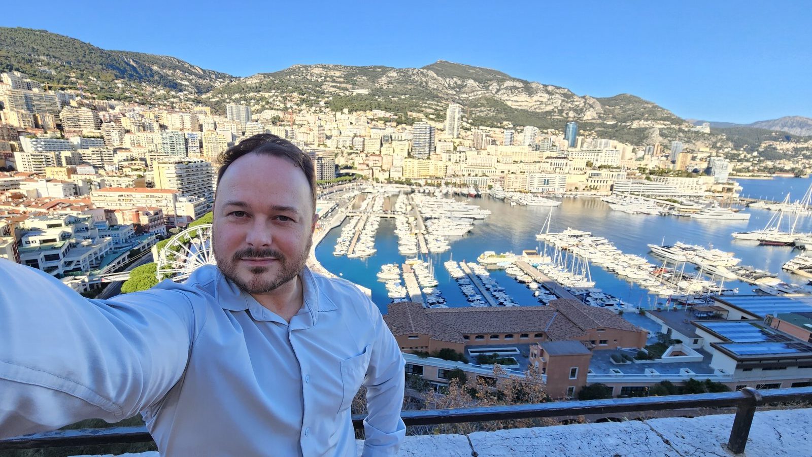 Benny taking a selfie above the harbour of Monaco, yachts and apartment blocks behind him