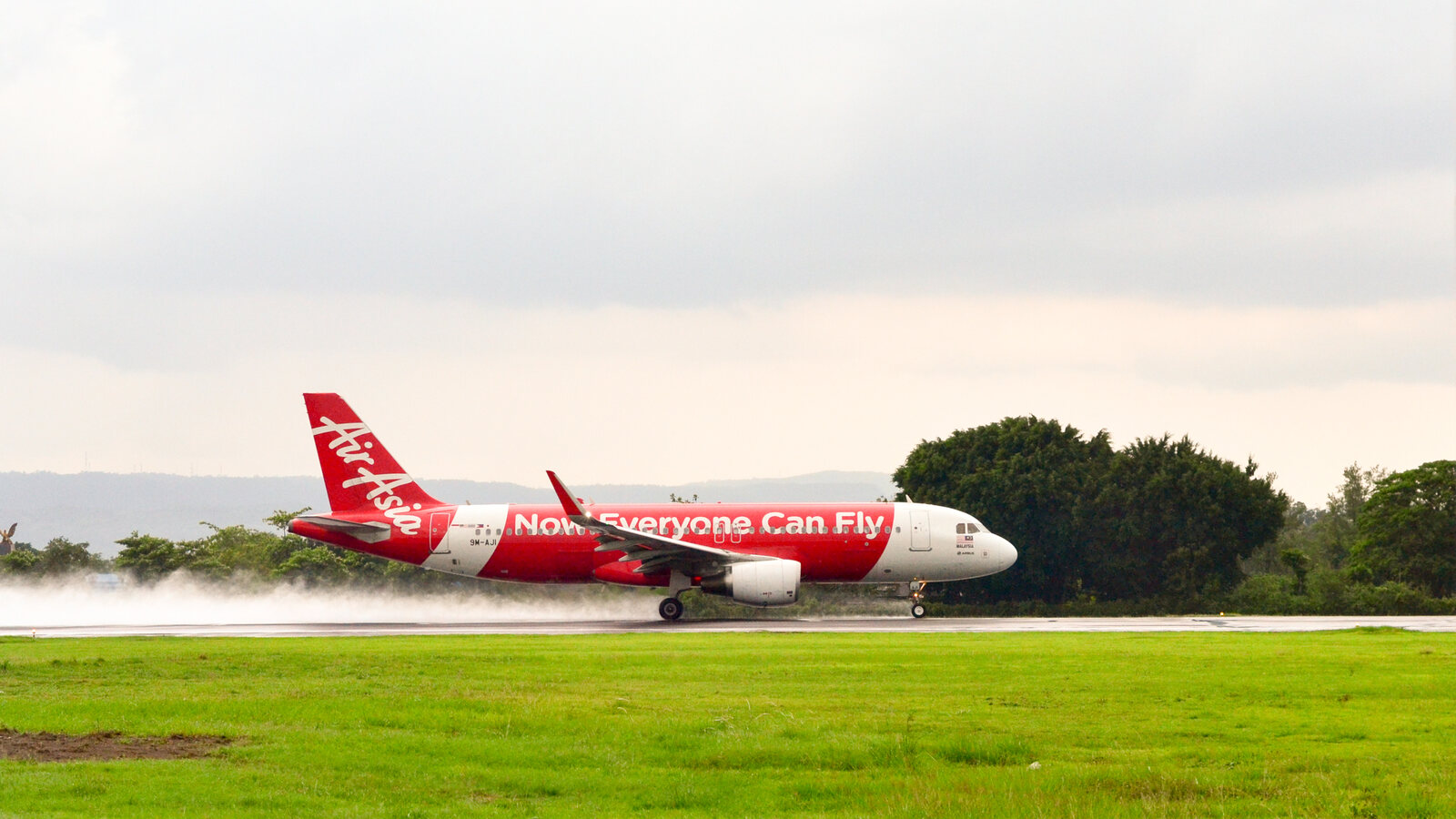 AirAsia passenger plane accelerating along a wet runway before take-off
