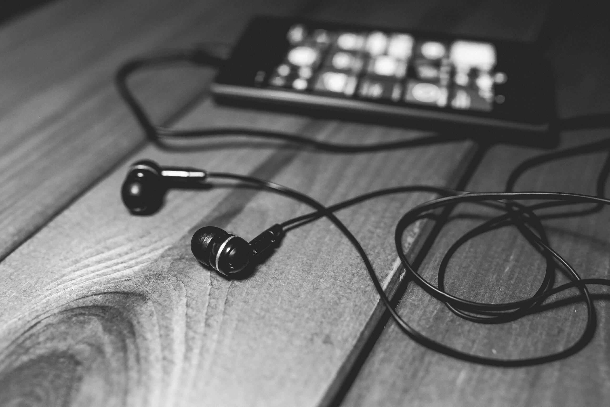 Earphones and a phone on a wooden table
