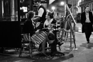 A waiter serving customers at a Paris café at night