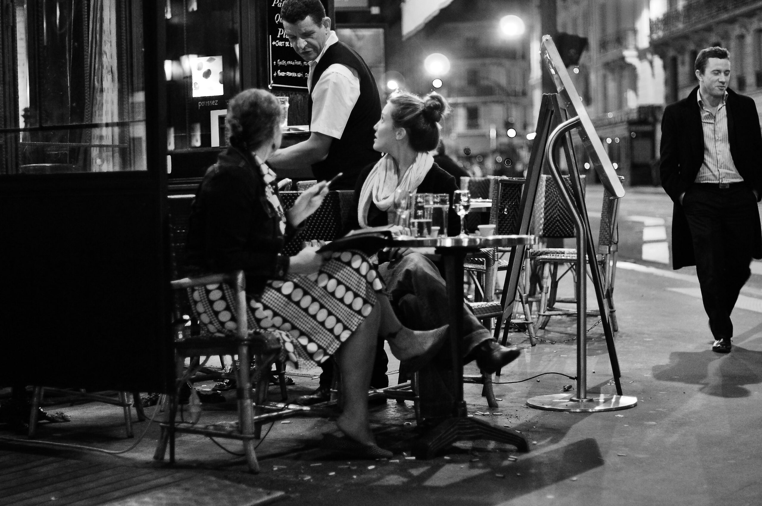 A waiter serving customers at a Paris café at night